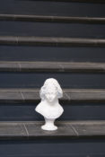 wyrzeźbione popiersie kobiece stoi przed schodkami