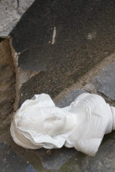 wyrzeźbione popiersie kobiece stoi na ziemi - kadr mocno przekrzywiony