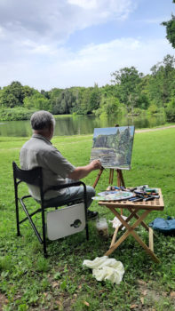 mężczyzna maluje z natury pejzaż w parku 